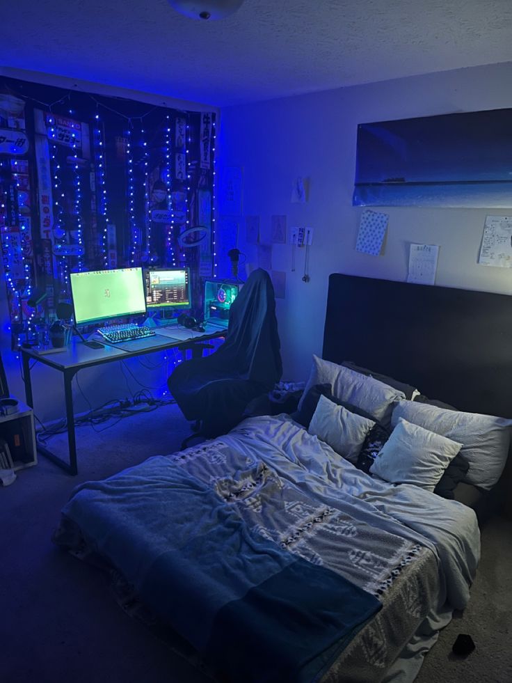 a bedroom with two computer monitors on the wall and a bed in the foreground