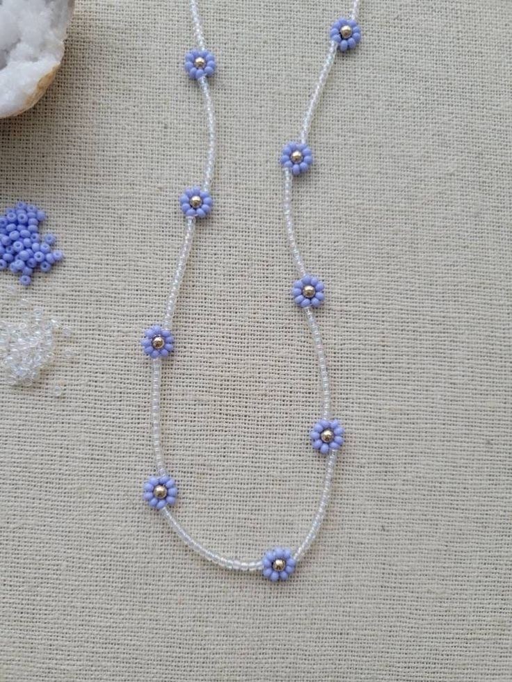 a necklace with blue flowers on it and some beads hanging from the side of it