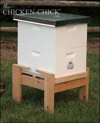 a beehive sitting in the grass with two bees on it's legs