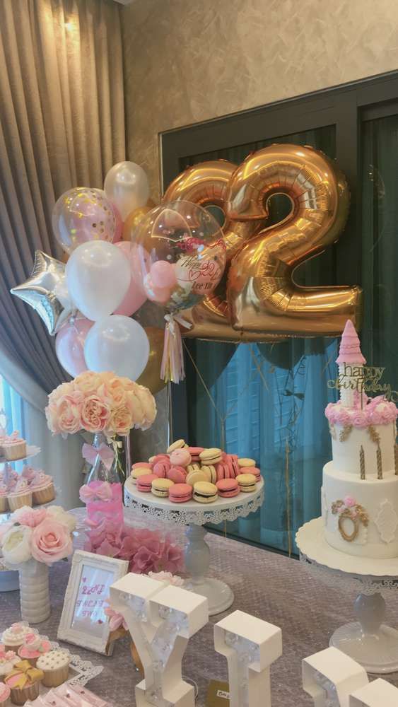 a table topped with lots of desserts and balloons in front of a number twenty sign