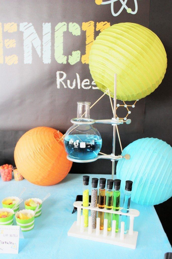 a table topped with lots of bottles filled with liquid next to orange and blue balls