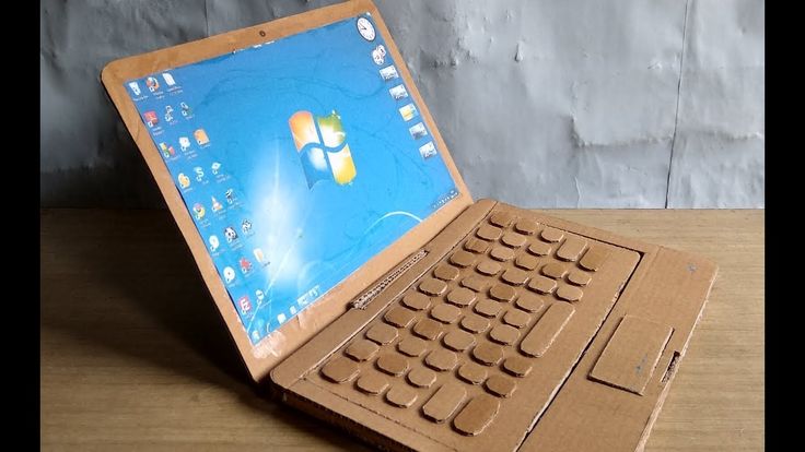 an open laptop computer sitting on top of a wooden table next to a brick wall