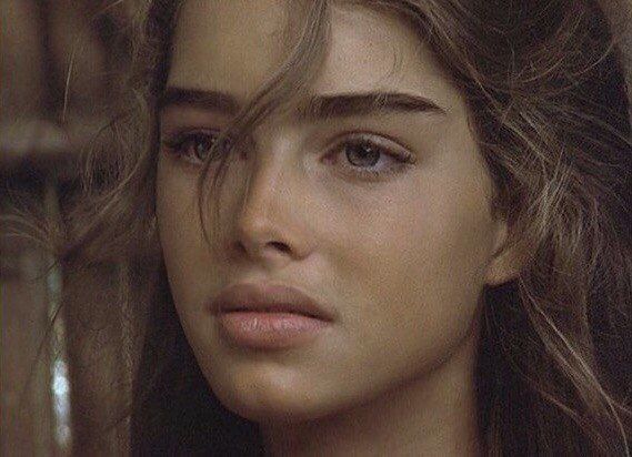 a close up of a woman's face with hair blowing in the wind