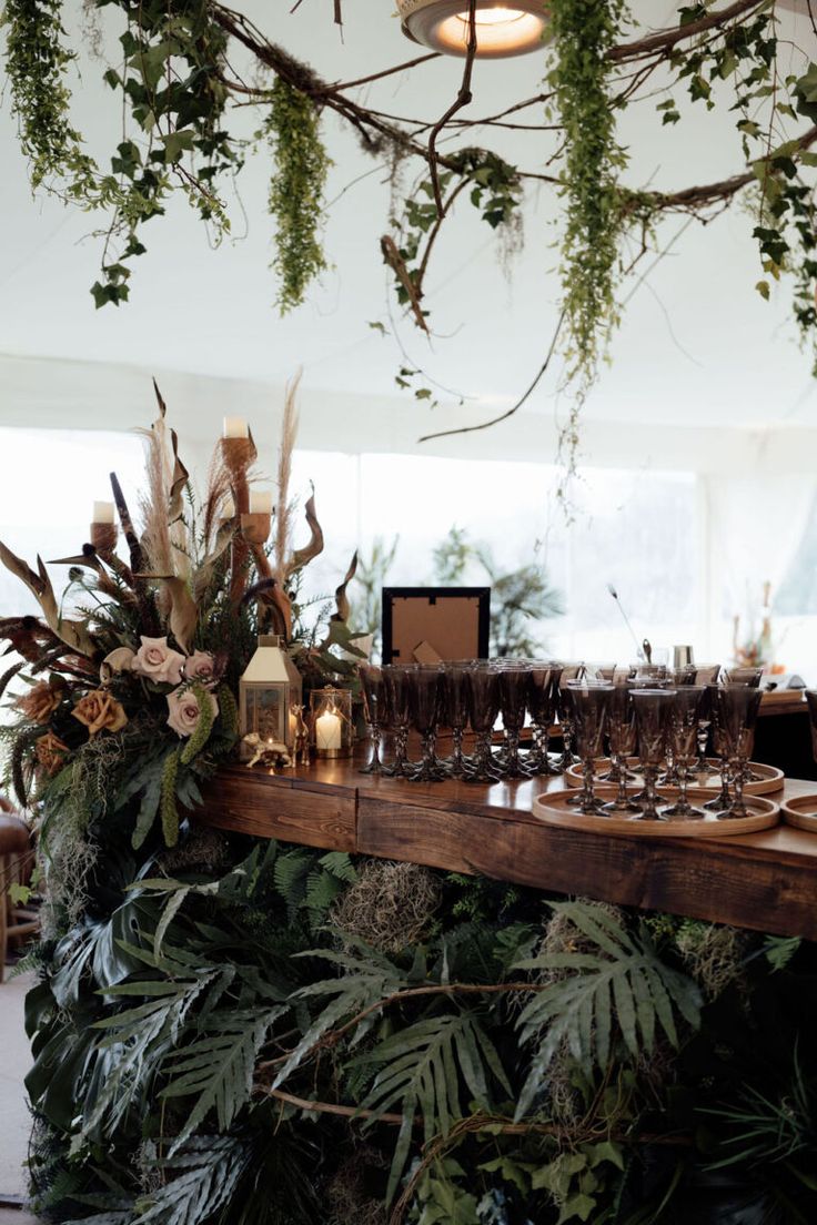 the table is set with wine glasses and greenery