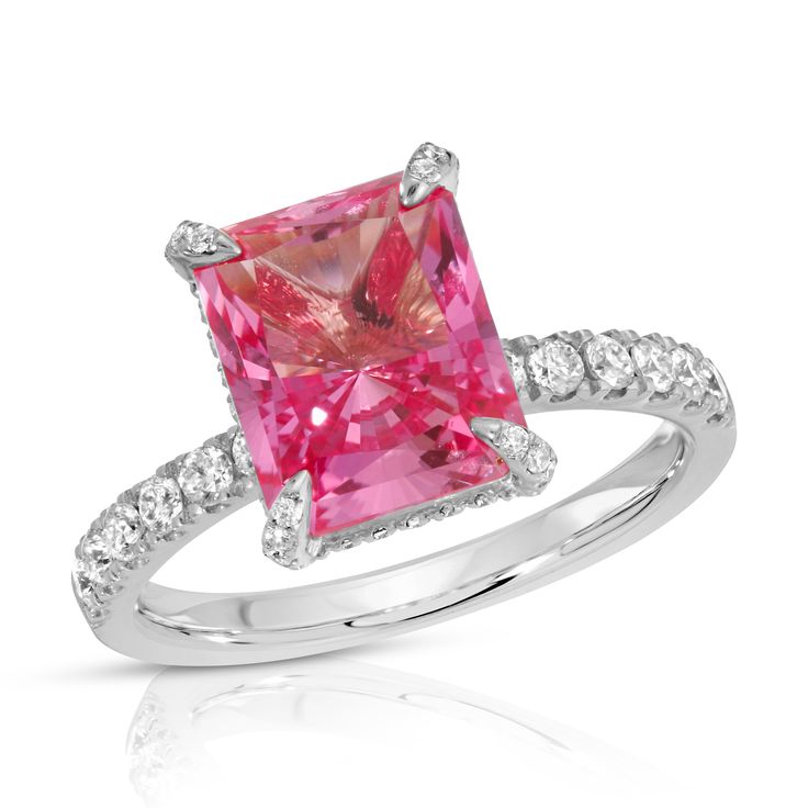 The radiant cut, cultured pink sapphire at the center of this playful ring represents the color of fiery passion for love and for life. A moissanite hidden halo and encrusted prongs offer just the right amount of sparkle to this feminine and charming ring. Made to order. Please allow 6-8 weeks for delivery.DETAILS:Center Stone: Type: Pink Sapphire (cultured) Size: 8 x 10mm (3.5ct diamond equivalent) Color: Pink Cut: Radiant Setting: Moissanite hidden halo and encrusted prongs 10K, 14K or 18K sol Fine Jewelry Pink Halo Ring With Accent Stones, Radiant Cut Sapphire Ring With Accent Stones, Pink Diamond Halo Promise Ring, Pink Emerald Cut Ruby Ring In Fine Jewelry, Pink Emerald Cut Sapphire Ring In Fine Jewelry Style, Fine Jewelry Pink Emerald-cut Sapphire Ring, Emerald Cut Pink Ruby Ring In Fine Jewelry Style, Fine Jewelry Pink Sapphire Ring With Emerald Cut, Pink Emerald Cut Sapphire Ring Fine Jewelry