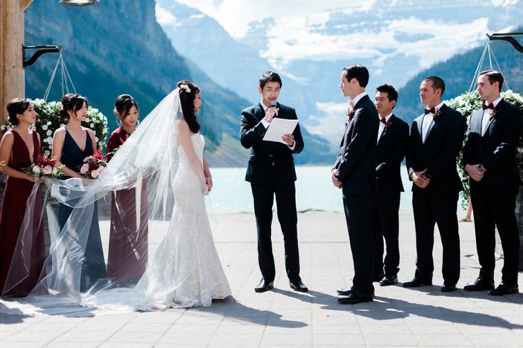 a bride and groom standing in front of their wedding party