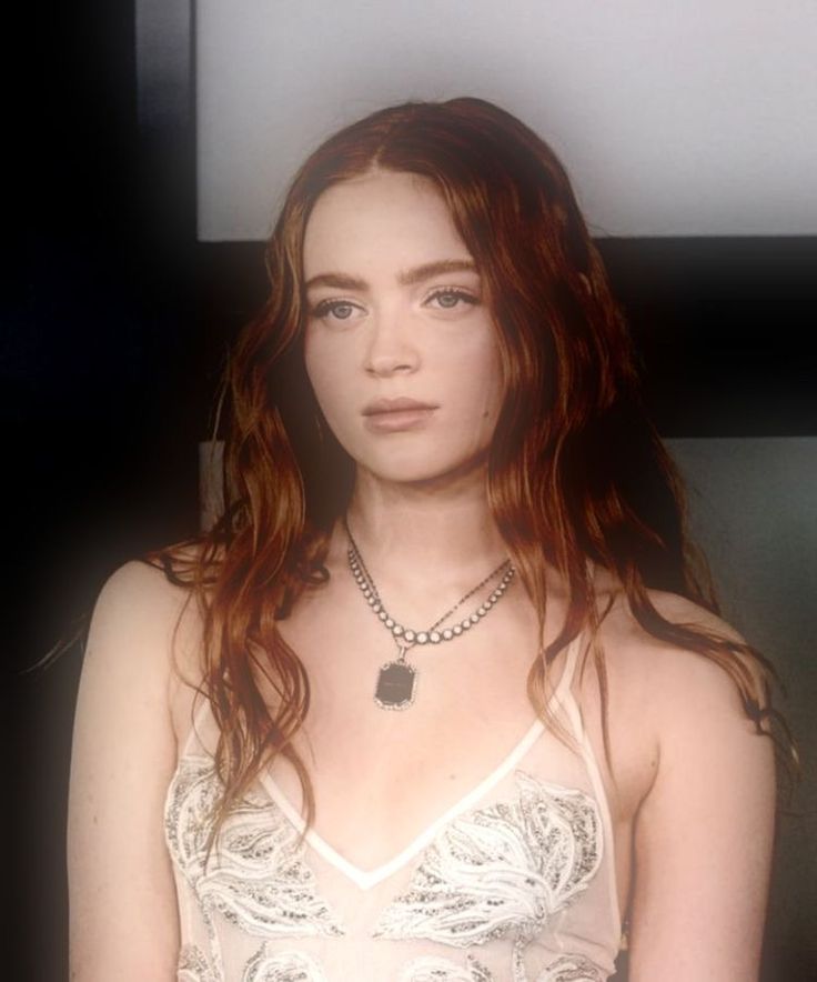 a woman with long red hair wearing a white top