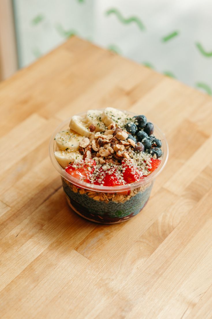 a bowl filled with fruit and nuts on top of a wooden table