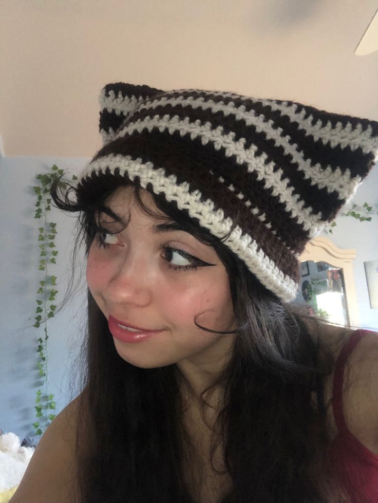 a young woman wearing a crocheted hat and looking at the camera while smiling