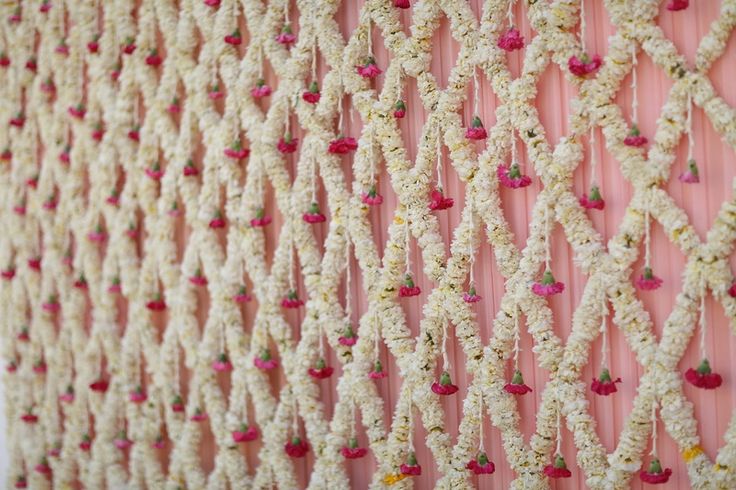 the wall is decorated with white crochet and red beads on pink yarns