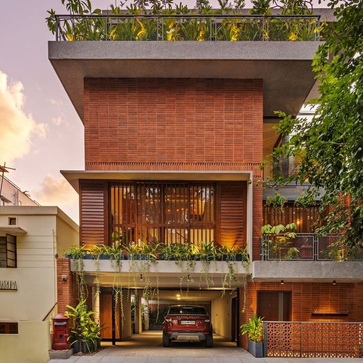 a car parked in front of a building with plants growing on the balconies