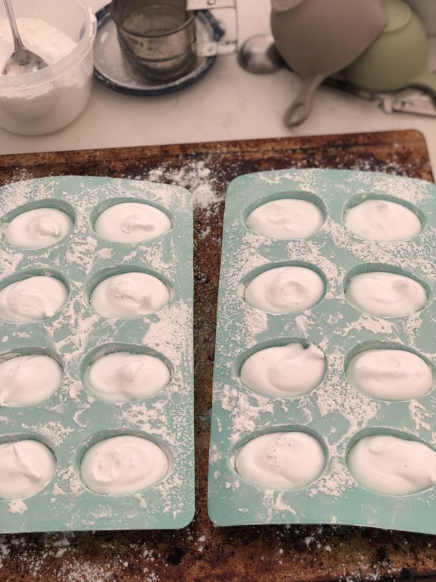 two trays filled with icing sitting on top of a counter