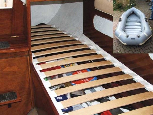 a bed with wooden slats and an inflatable boat on the floor next to it