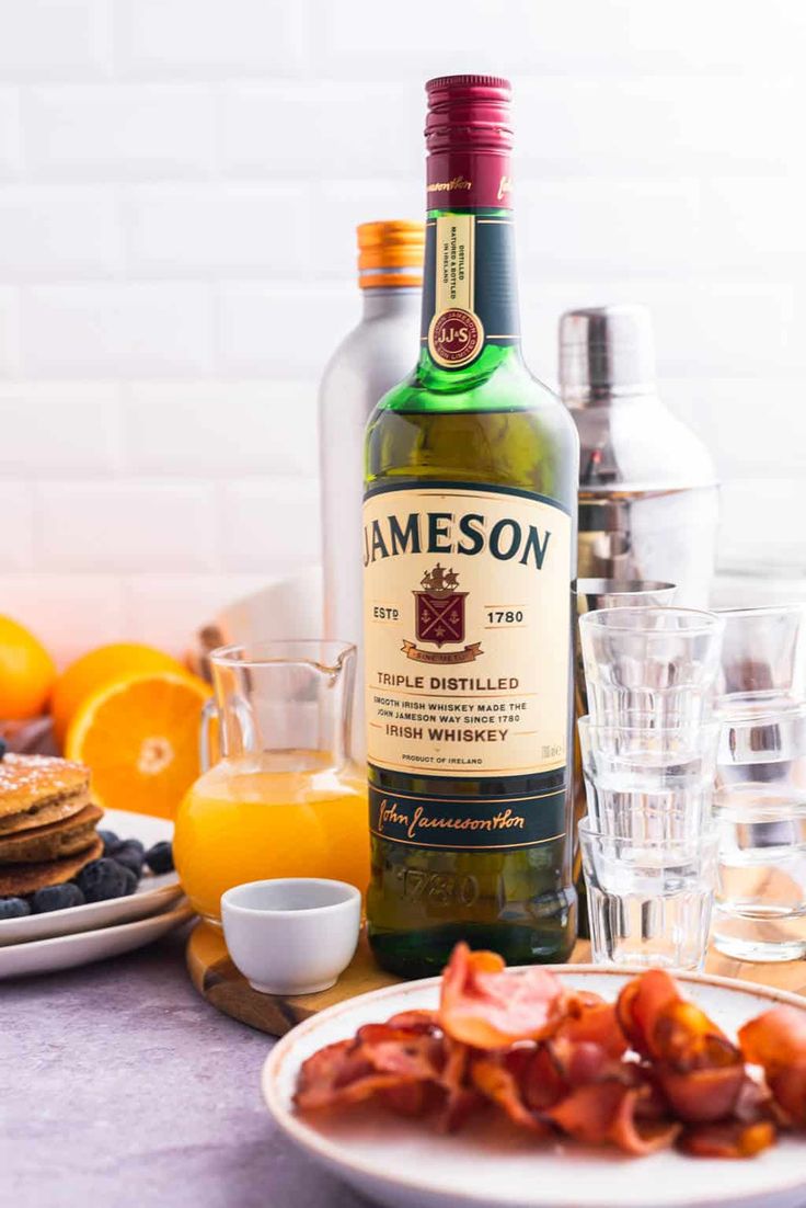 a bottle of jameson sitting on top of a table next to plates of food and glasses