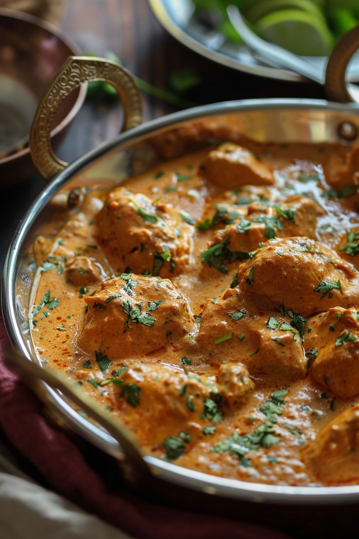 a metal pan filled with meatballs covered in sauce and garnished with parsley