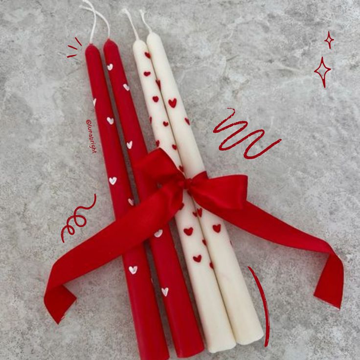 three candles tied together with red ribbon and hearts on them for valentine's day