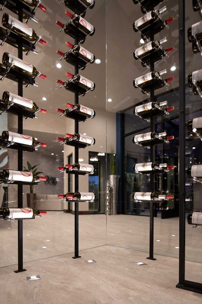 a room filled with lots of bottles of wine on top of metal poles in front of a glass wall