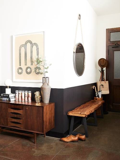 a wooden bench sitting in front of a wall mounted art on the side of a white wall