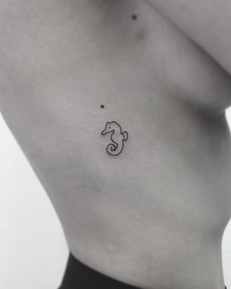 a black and white photo of a woman's stomach with a sea horse tattoo on it