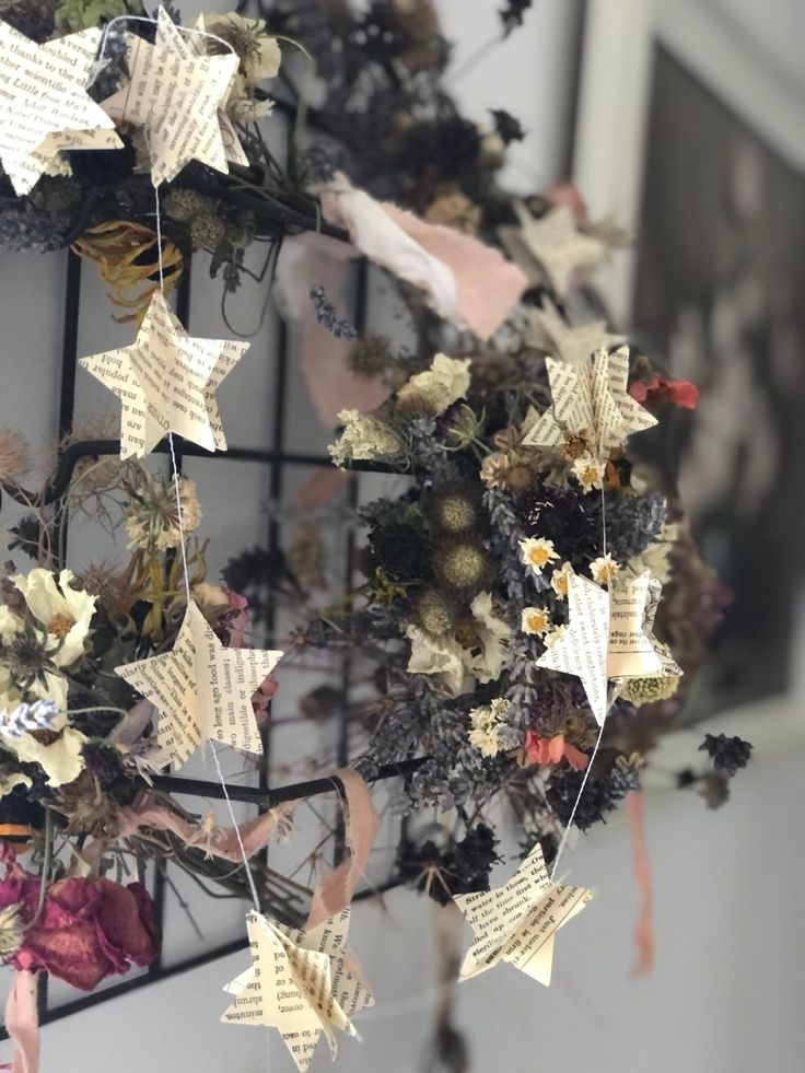 a wreath made out of old book pages hanging from a wire rack with paper stars attached to it