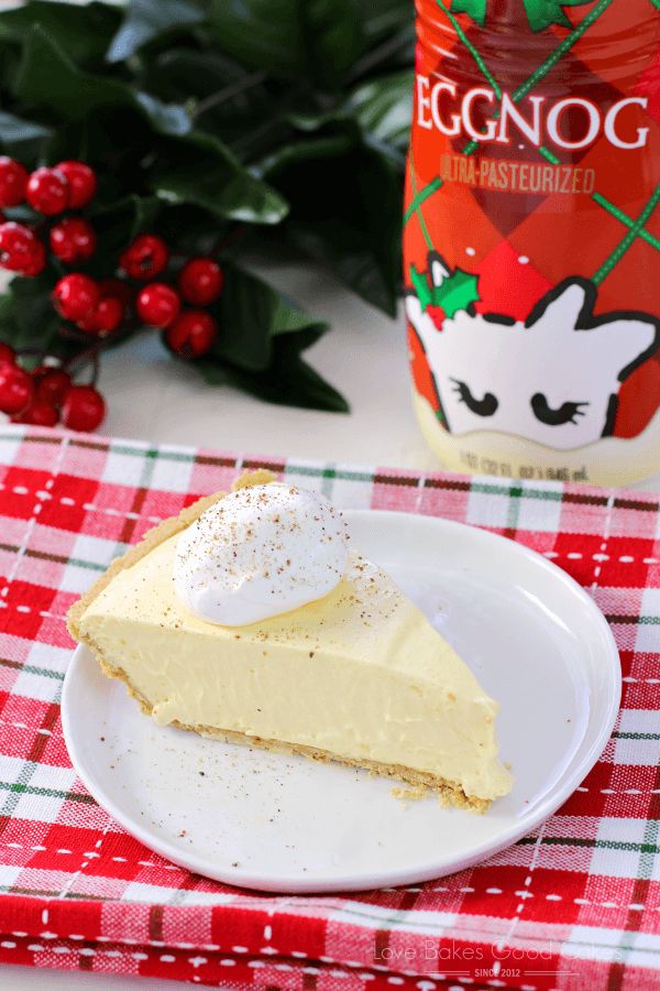 a slice of cheesecake on a plate next to a bottle of eggnog