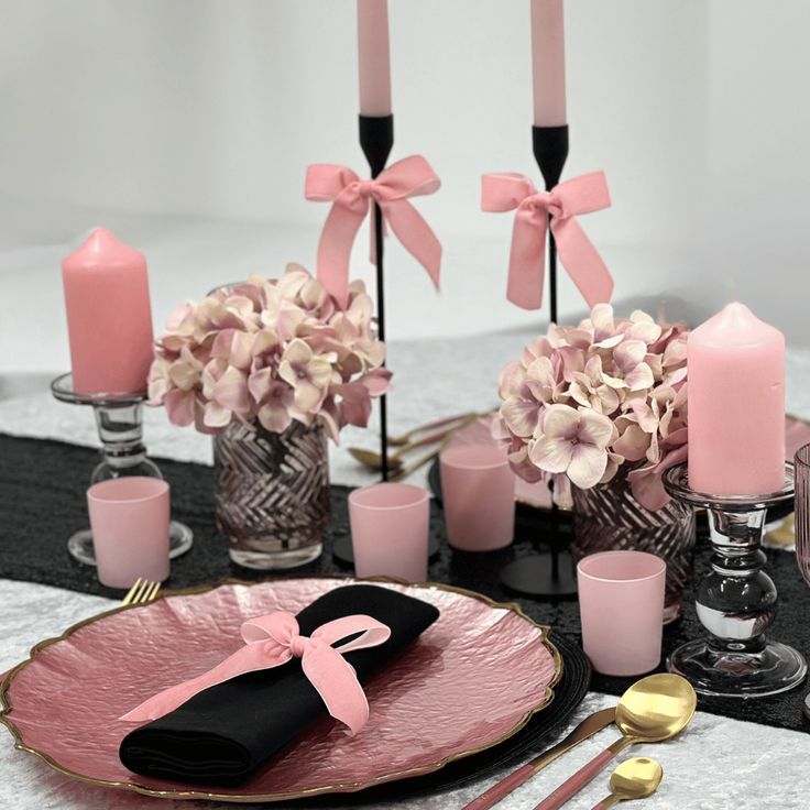 pink and black table setting with candles, napkins, flowers and utensils