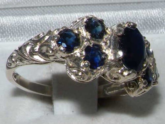 This Beautiful and Unusual Victorian Style Ring is made completely from Solid Sterling Silver and was Hallmarked in London, England. It has been hand set with a beautiful selection of Sapphires. These are genuine Sapphire Gemstones. These Colorful Blue Sapphire stand out wonderfully set against the polished Silver providing such an Elegant overall appearance. The ring also boasts a well crafted Art Nouveau Style carving on the shoulders of the ring. The ring has a good thick shank and a Highly P Heirloom Sapphire Jewelry In Sterling Silver, Heirloom Sterling Silver Sapphire Jewelry, Blue Heirloom Handmade Jewelry, Collectible Silver Sapphire Jewelry, Engraved Blue Sterling Silver Rings, Heirloom Blue Sapphire Ring In Sterling Silver, Heirloom Style Blue Jewelry With Polished Finish, Blue Engraved Sterling Silver Rings, Blue Sapphire Ring Stamped 925 For Wedding