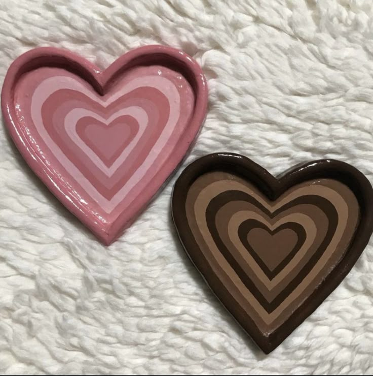 two heart shaped trays sitting on top of a white blanket