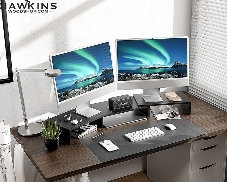 two computer monitors sitting on top of a wooden desk