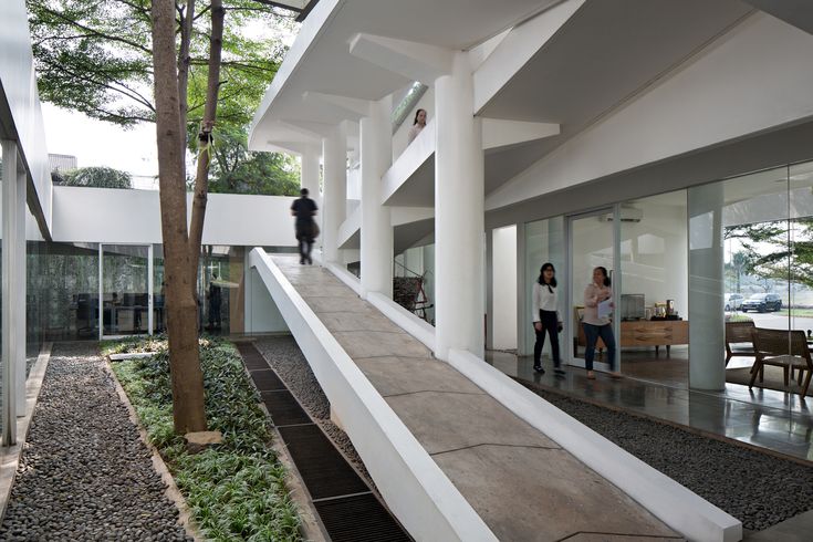 two people are walking up and down the stairs in a modern building with glass walls