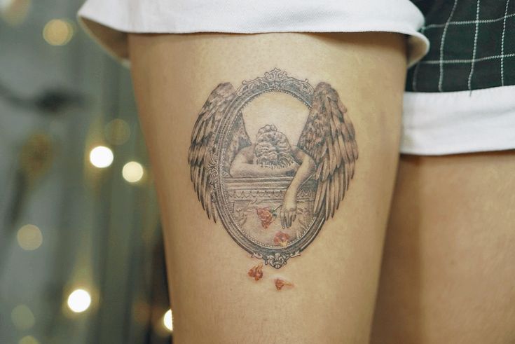 a woman's thigh with an angel tattoo on it