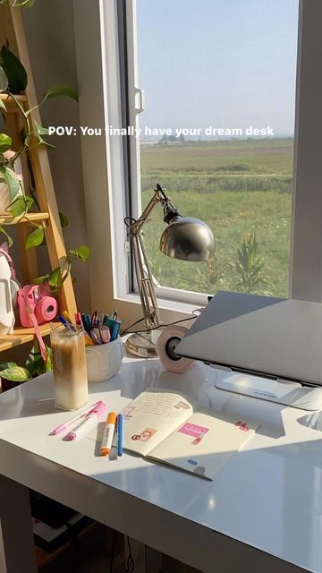 an open laptop computer sitting on top of a white desk in front of a window