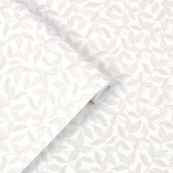 a white wallpaper with leaves on it and a roll of paper next to it