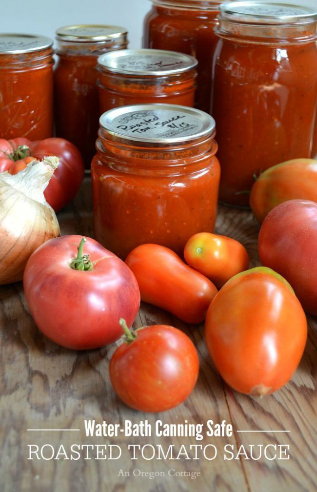 tomatoes, garlic, and other vegetables sit on a table with canning jars in the background