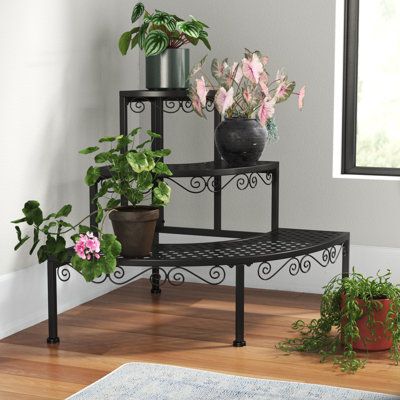 three tiered plant stand with potted plants on each shelf in front of a window