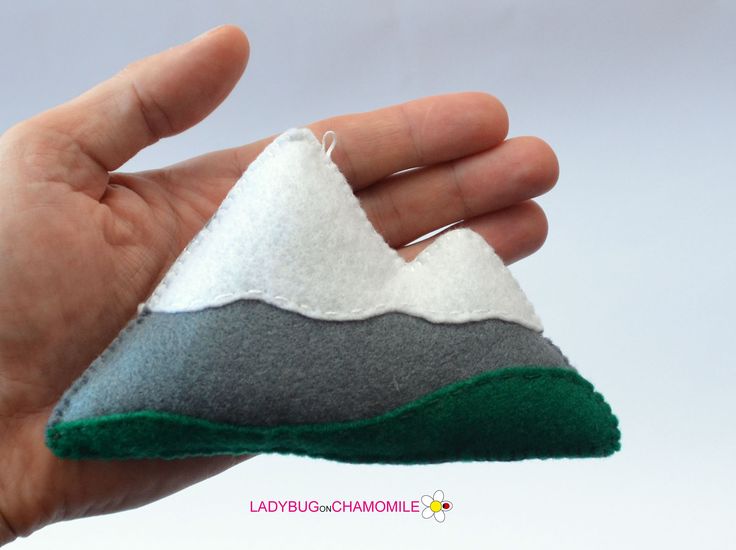 a hand holding a small felt mountain ornament