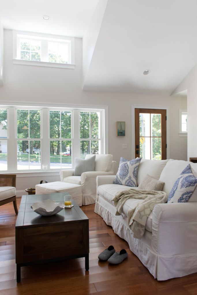 a living room filled with white furniture and lots of windows in the wall behind it