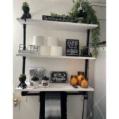 shelves with candles, plants and pictures on them in a white bathroom decorated for halloween