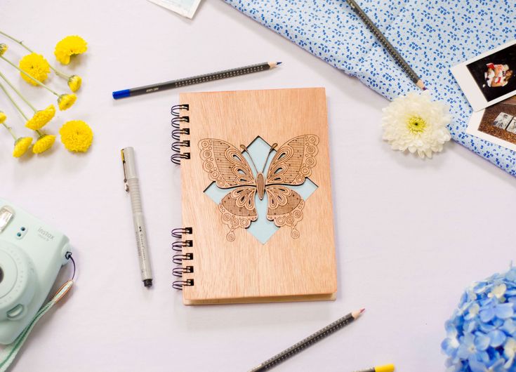 a wooden notebook sitting on top of a table next to some flowers and other items