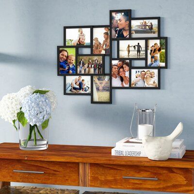 a wooden table topped with a vase filled with white flowers and pictures on the wall