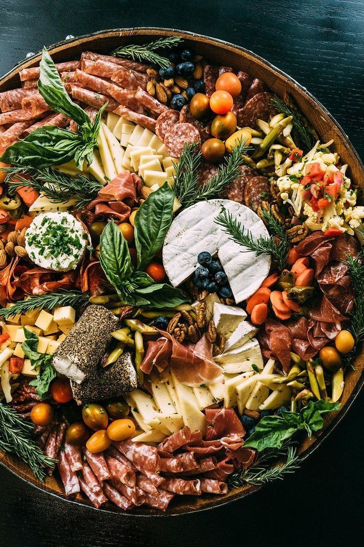 a platter filled with meats, cheese and other foods on top of a table