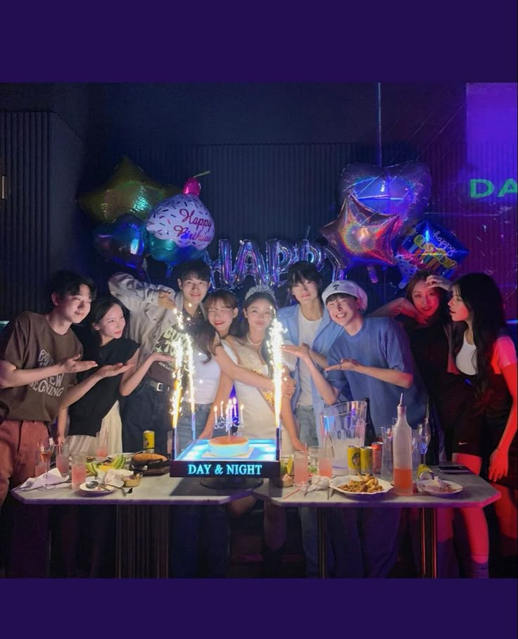 a group of people standing in front of a table with a cake and candles on it