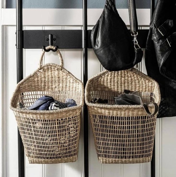 two wicker baskets are hanging on the wall next to a coat rack and purse