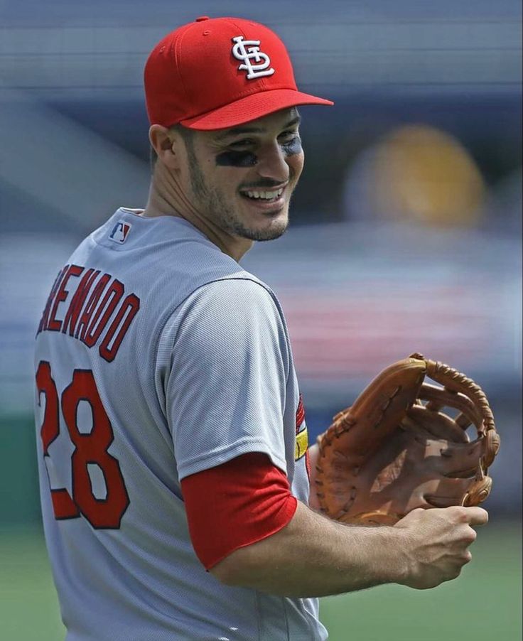 a baseball player holding a catchers mitt in his right hand and smiling at the camera