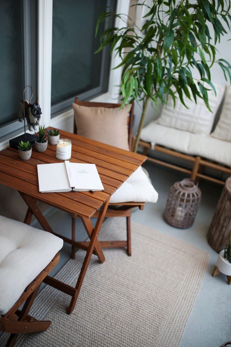 a wooden table sitting on top of a rug next to a window filled with potted plants