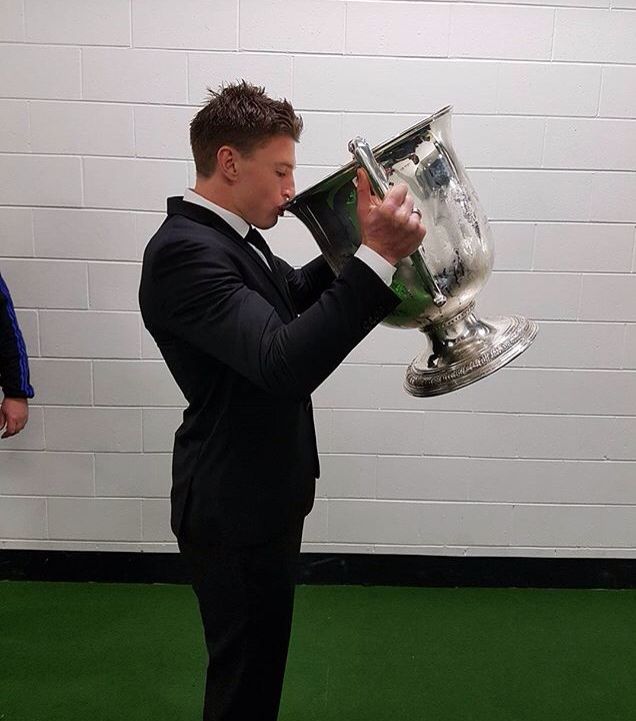 a man in a suit holding up a trophy