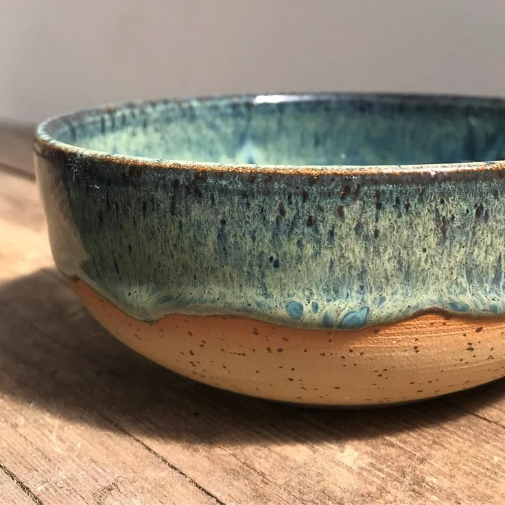 a blue and brown bowl sitting on top of a wooden table