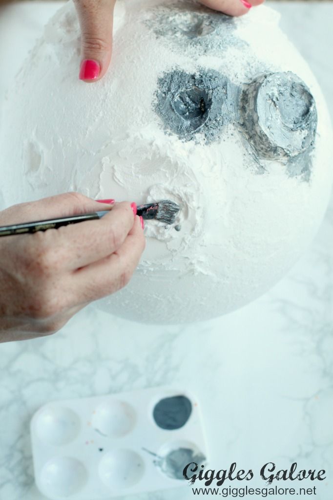 someone is painting a snowman on a white ball with red nail polish and scissors