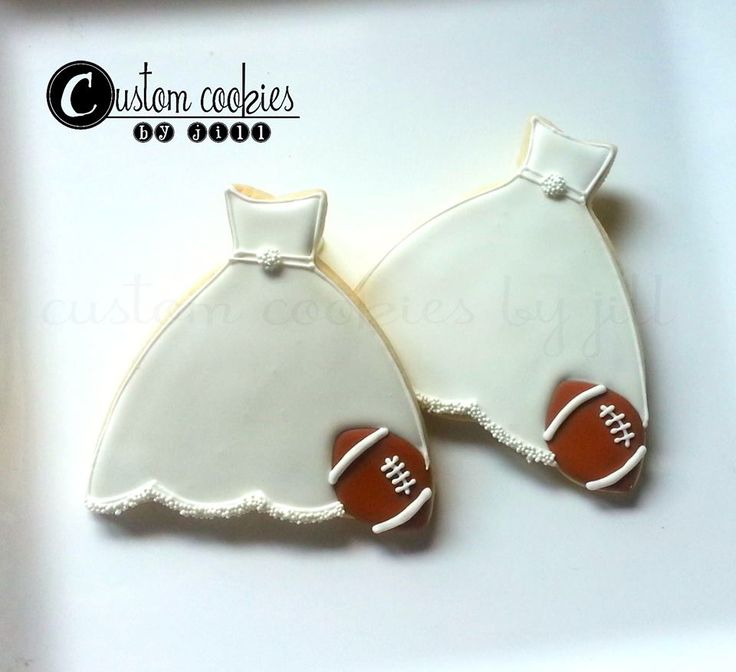 two decorated cookies in the shape of dresses with footballs on them are sitting on a white plate