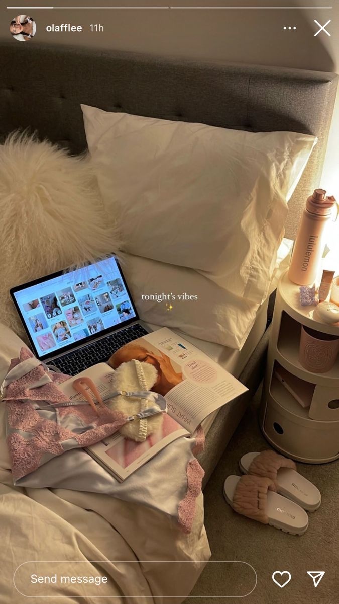 an open laptop computer sitting on top of a bed next to pillows and slippers